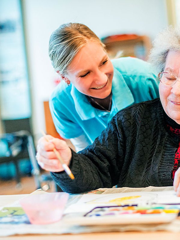 Eine Pflegerin und eine ältere Person beim Zeichnen