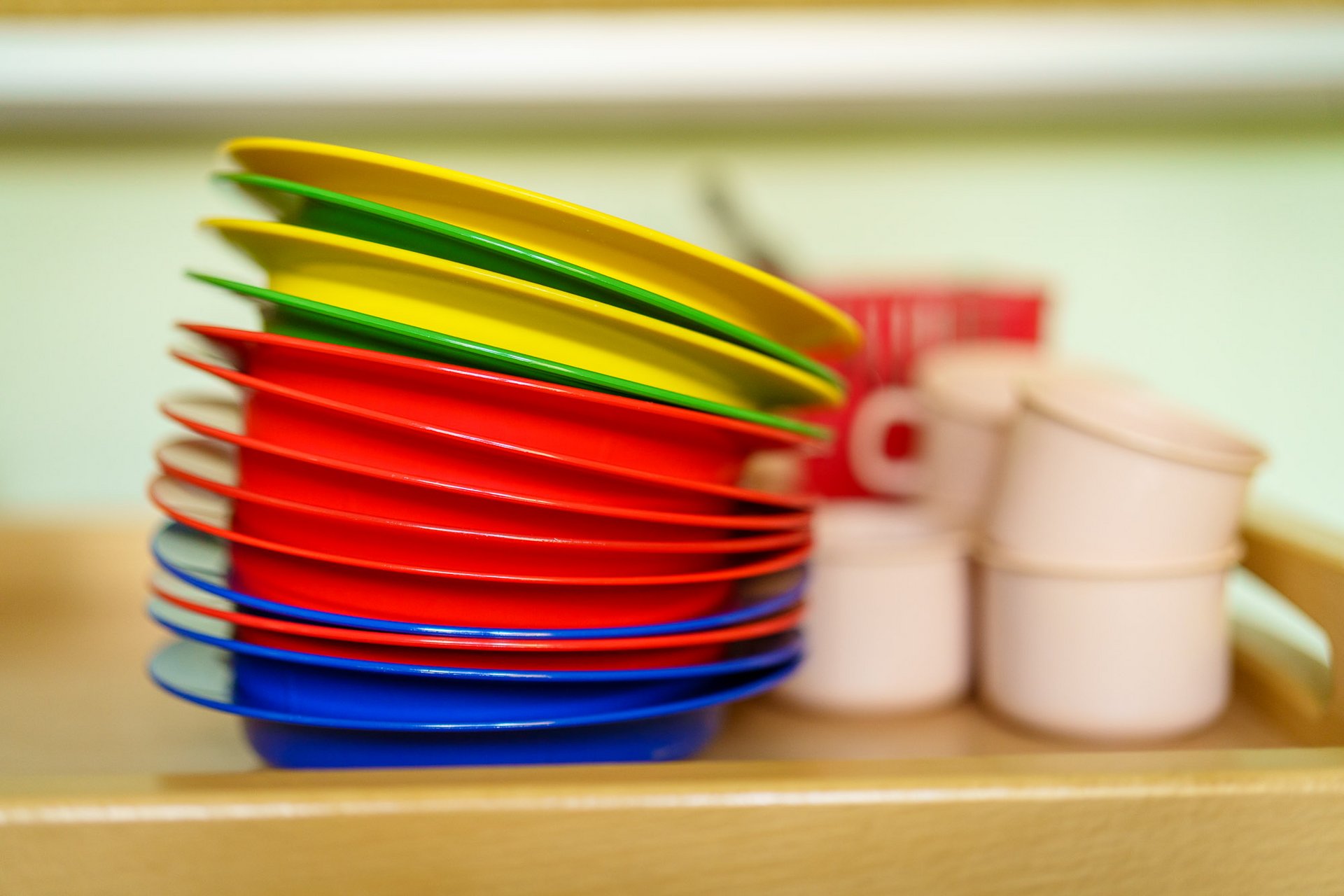 Zu sehen sind ein Stapel bunter Plastikteller und einige Plastik Tassen